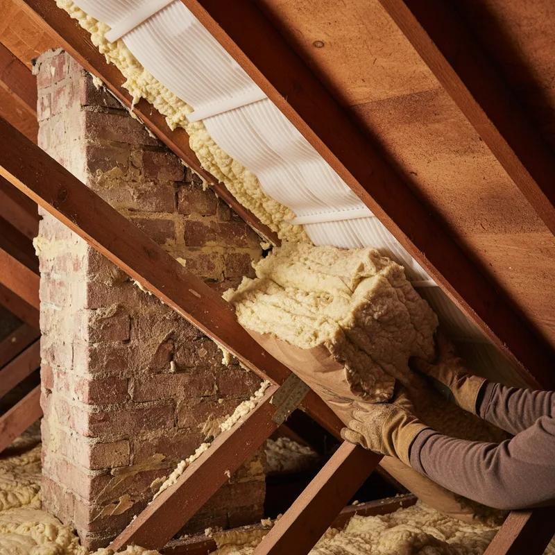 Contractor installing blown-in attic insulation in the attic of a Philadelphia row home as part of an ice dam prevention project